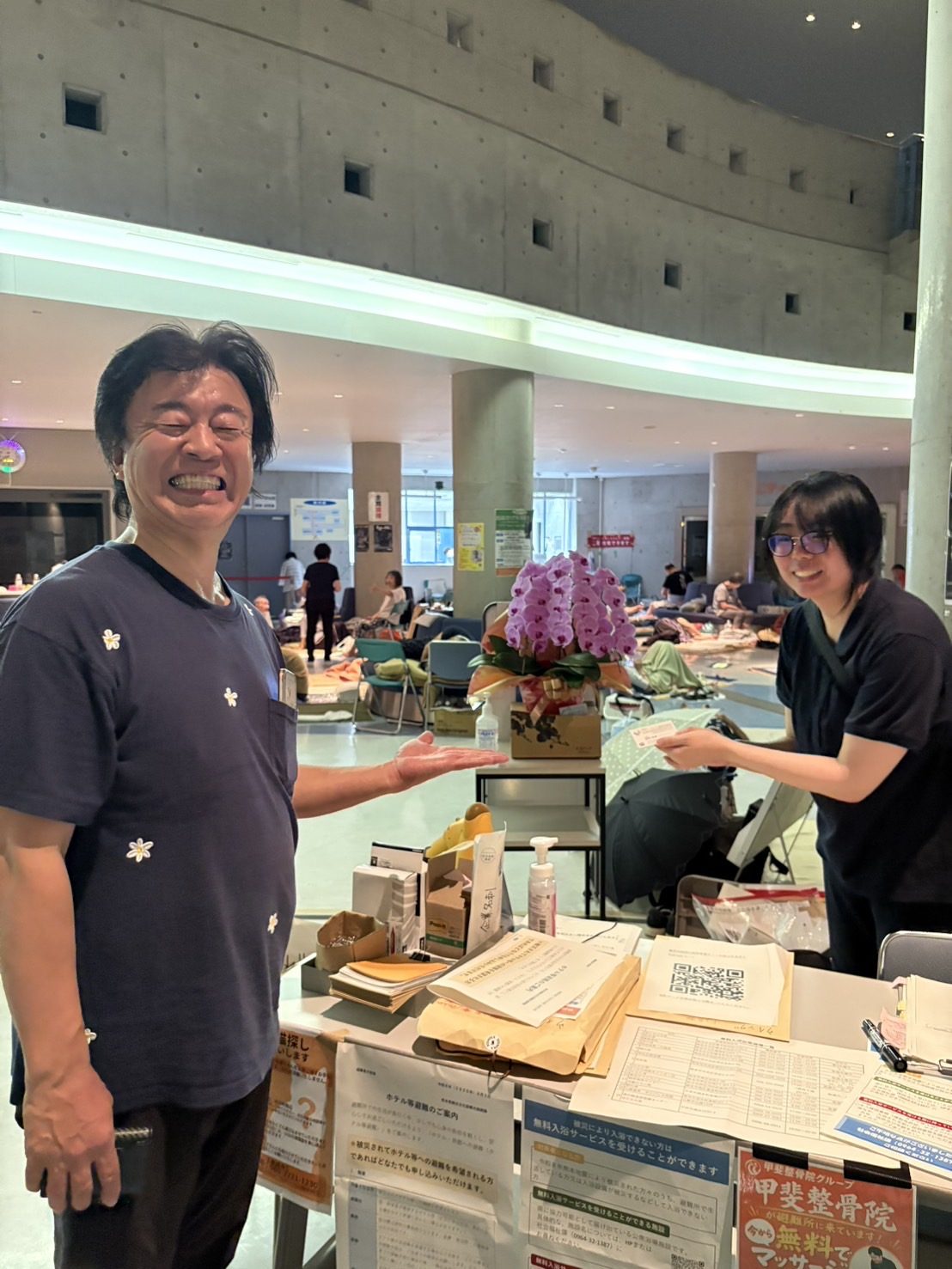 避難所で胡蝶蘭を受け取り、笑顔になる男性